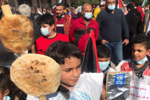 لاجئون بغزة يحملون أكياس دقيق فارغة وأرغفة خبز احتجاجا على تقليص خدمات الأونروا