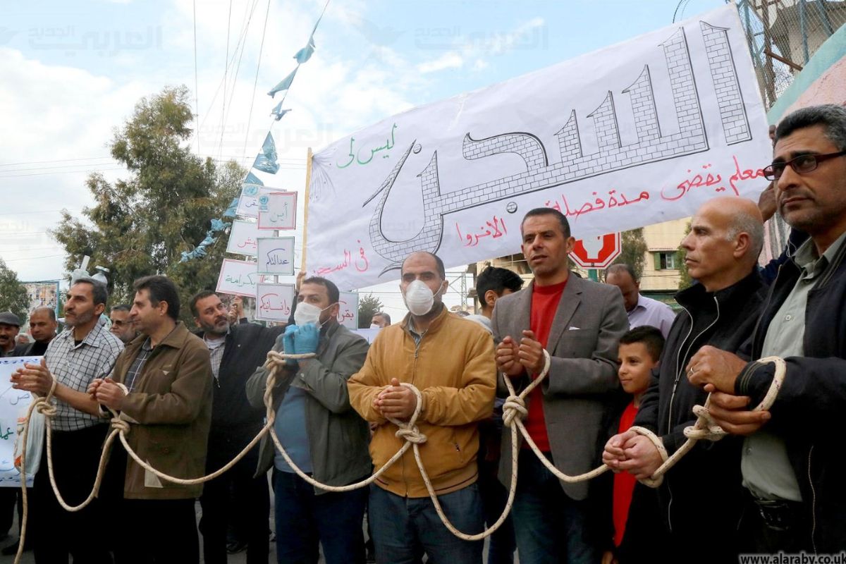 موظفون مفصولون من الأونروا يقيّدون أياديهم ويحتجون برفقة أطفالهم في غزة